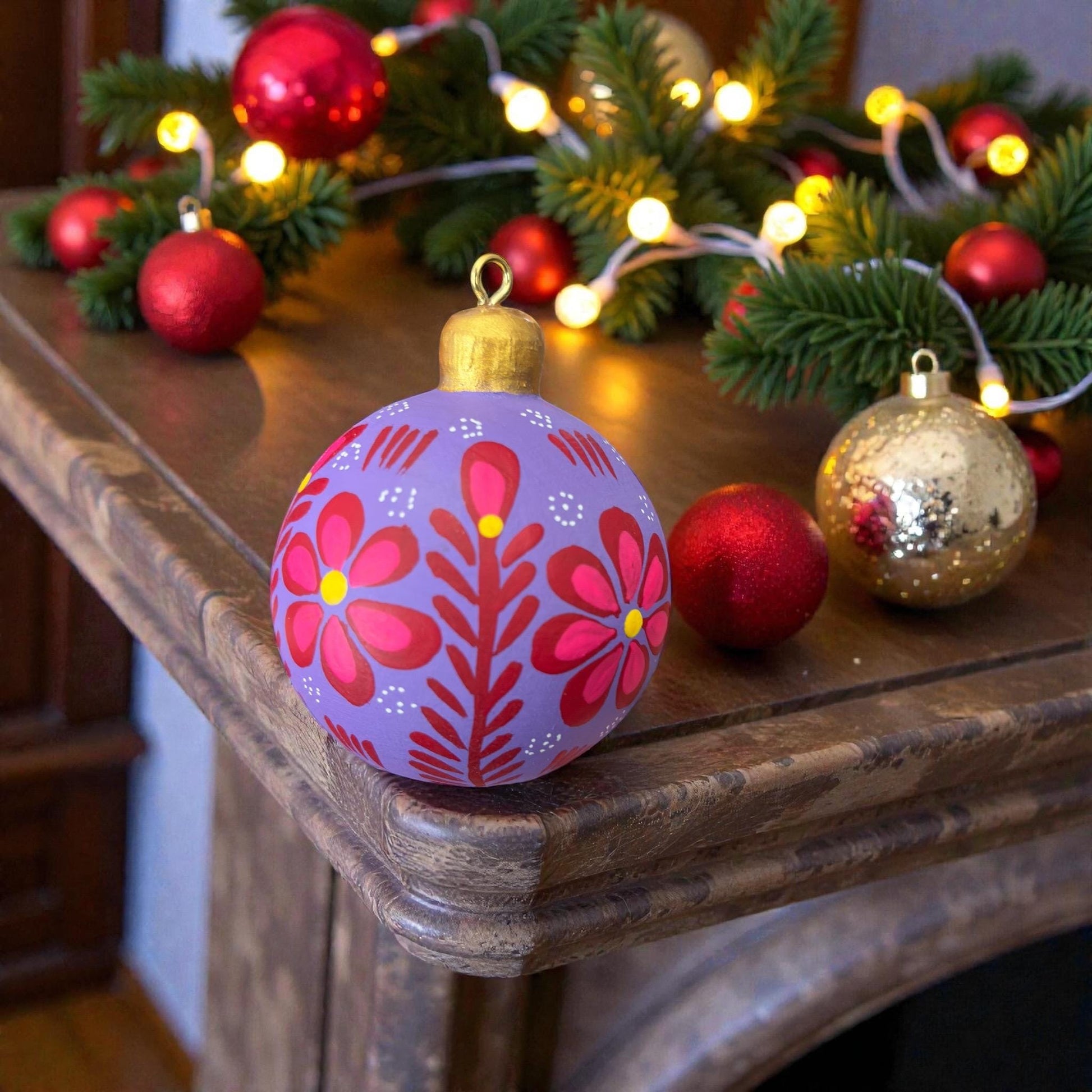 Hand-painted wooden Christmas ornament with floral design hanging on a Christmas tree