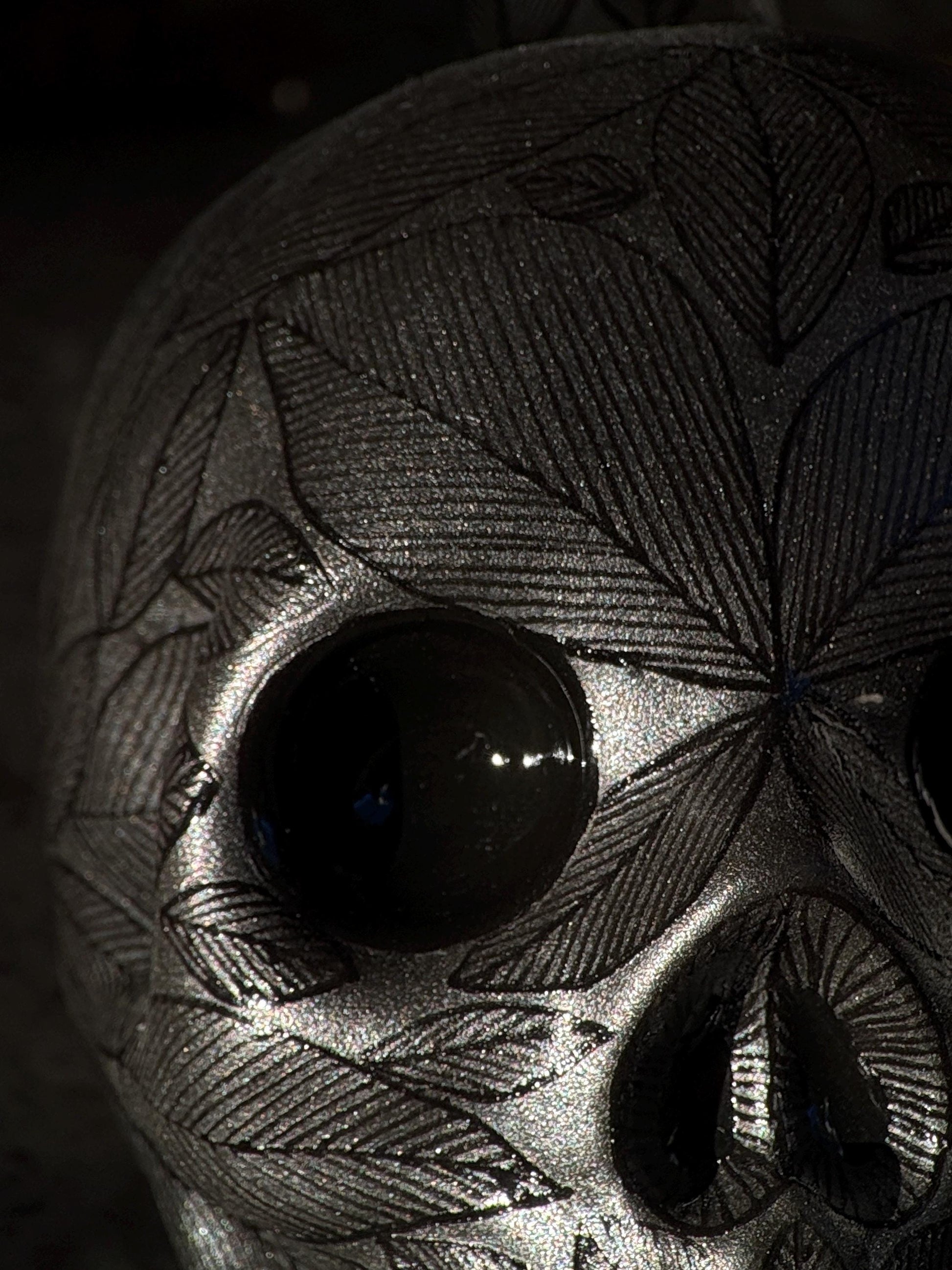 Close-up of the carved leaf pattern on a black stoneware skull decanter, handmade Mexican folk-art detail