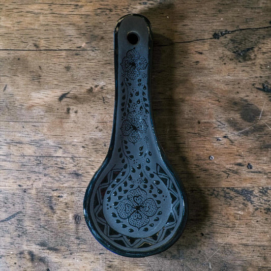 Black spoon rest holding wooden spoon - Mexican pottery