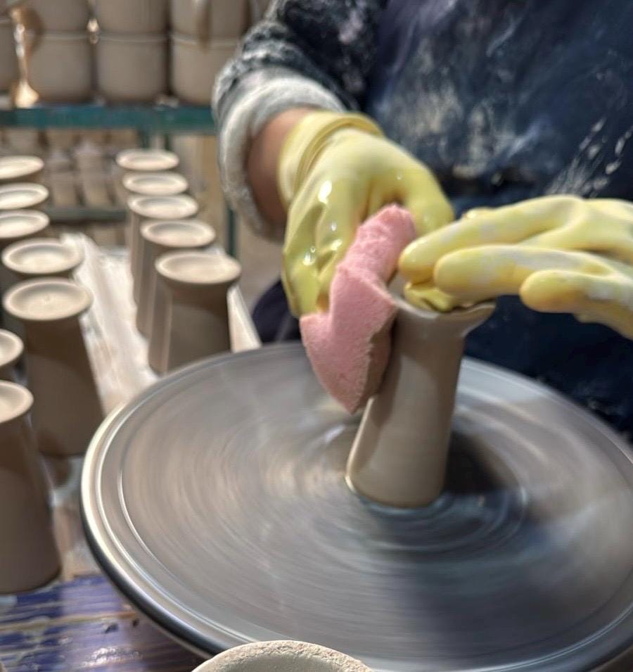 Artisan shaping a shot glass on a pottery wheel, showing how the handmade Mexican stoneware set is made
