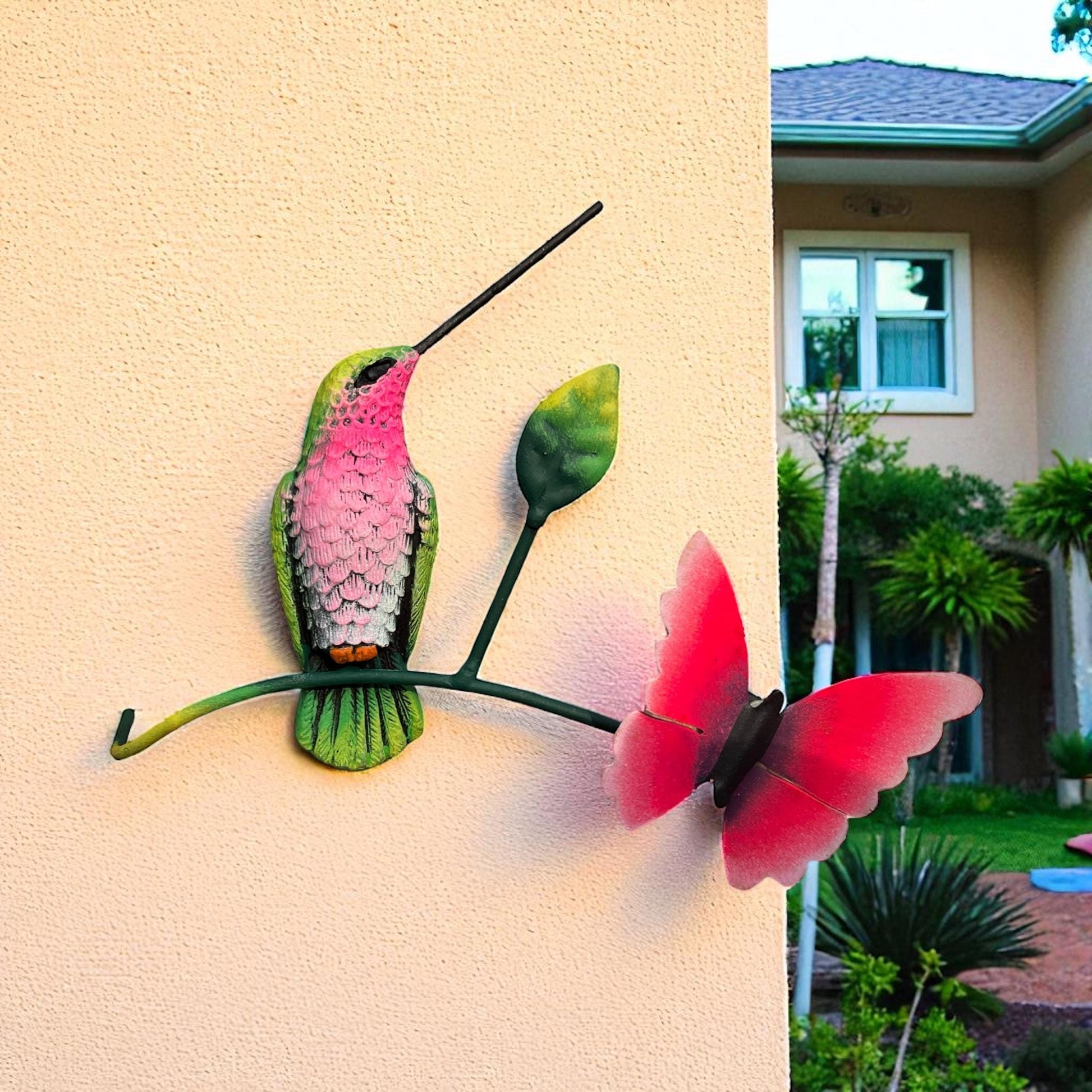 Green and pink metal hummingbird on wall with butterfly, Mexican wall decor