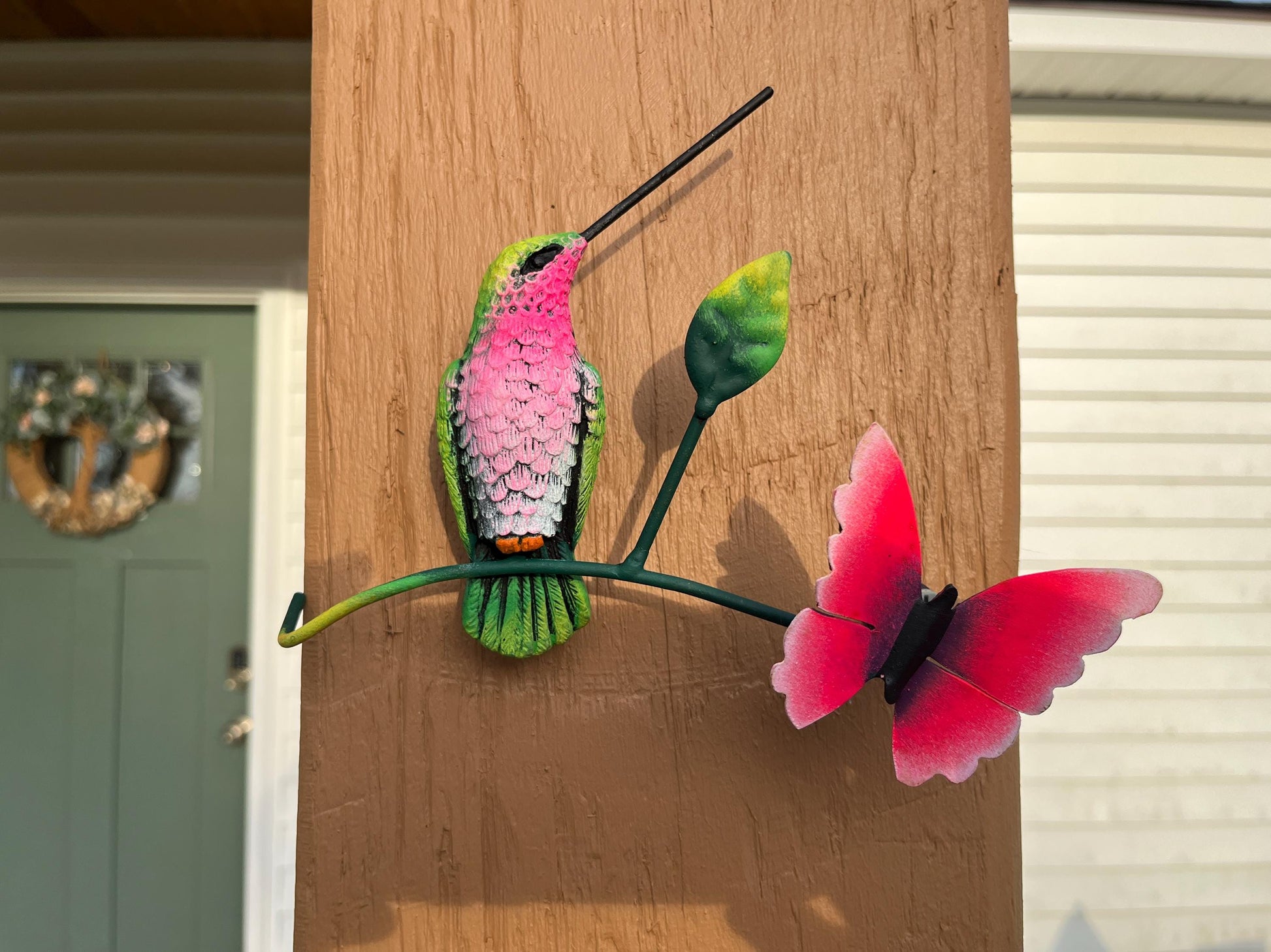 Green and pink metal hummingbird wall decor angled view, handmade Mexican wall art