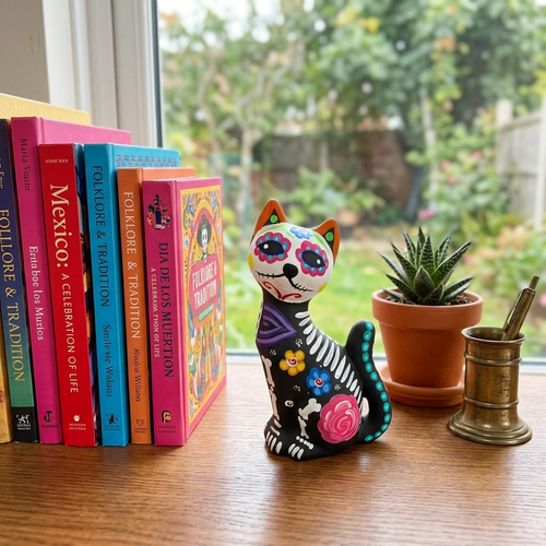 Mexican folk art cat alebrije with white skeleton bones and vivid painted flowers for Day of the Dead decor