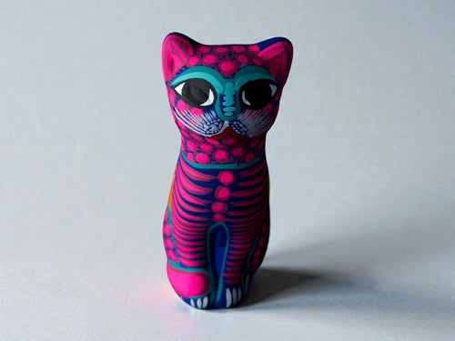 Pink clay cat alebrije with teal eyes and floral details, handmade Mexican folk art figurine